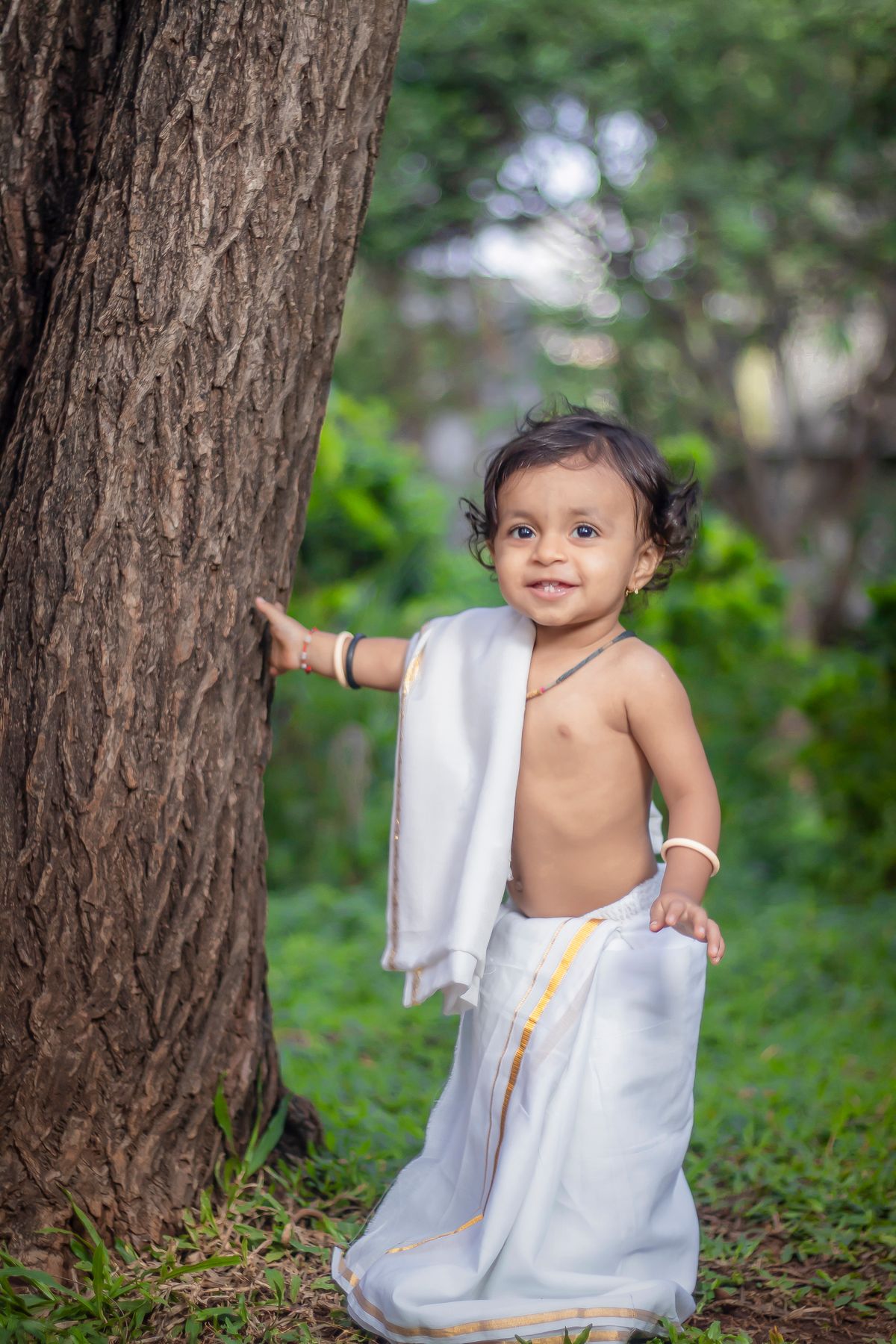 Child in costume standing beside a tree for first birthday photoshoot ideas