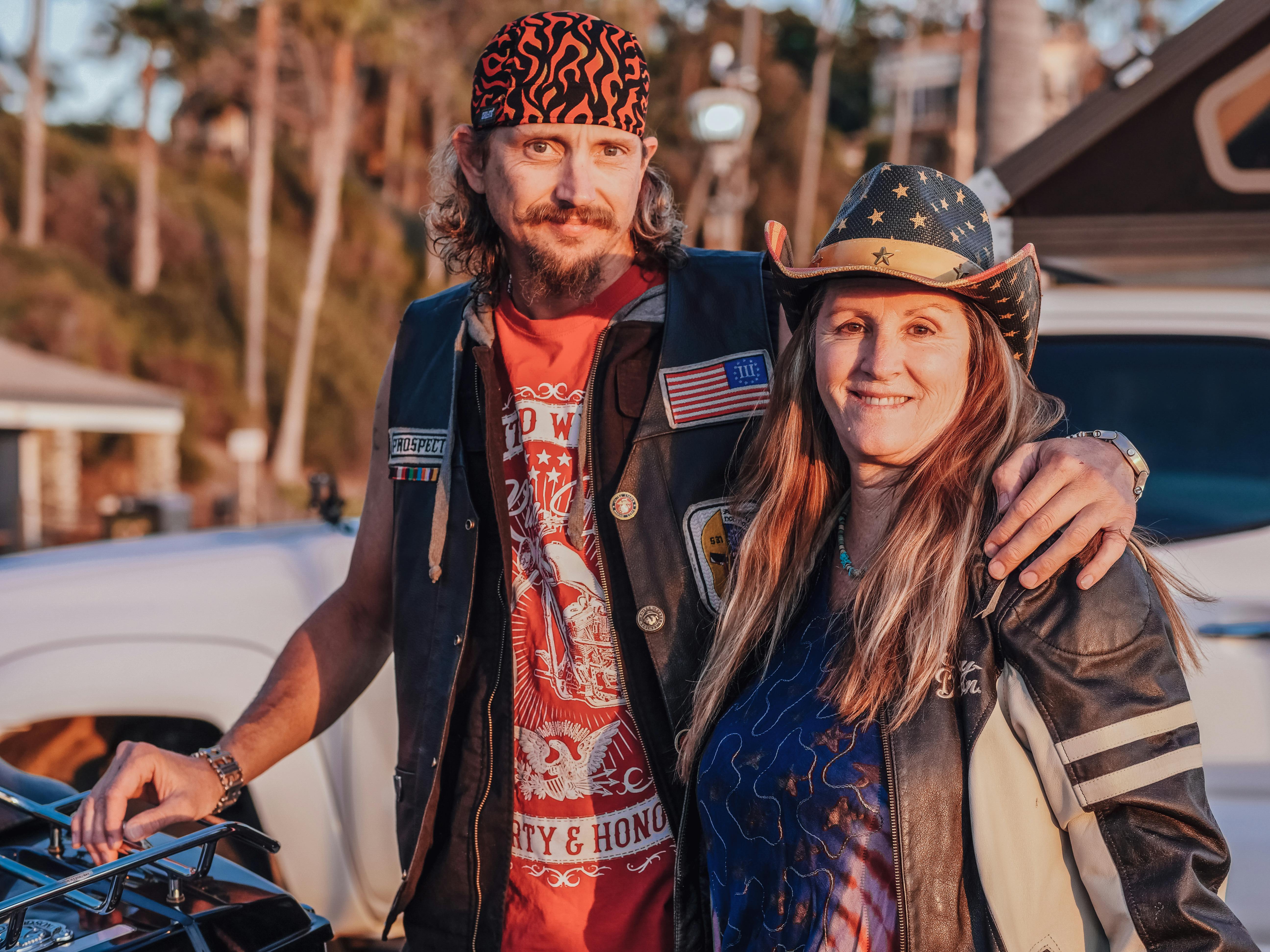 man in brown hat and blue denim jacket standing beside woman in red and white floral