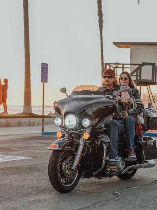 Free Senior couple on a motorcycle enjoying a scenic sunset ride by the beach. Stock Photo