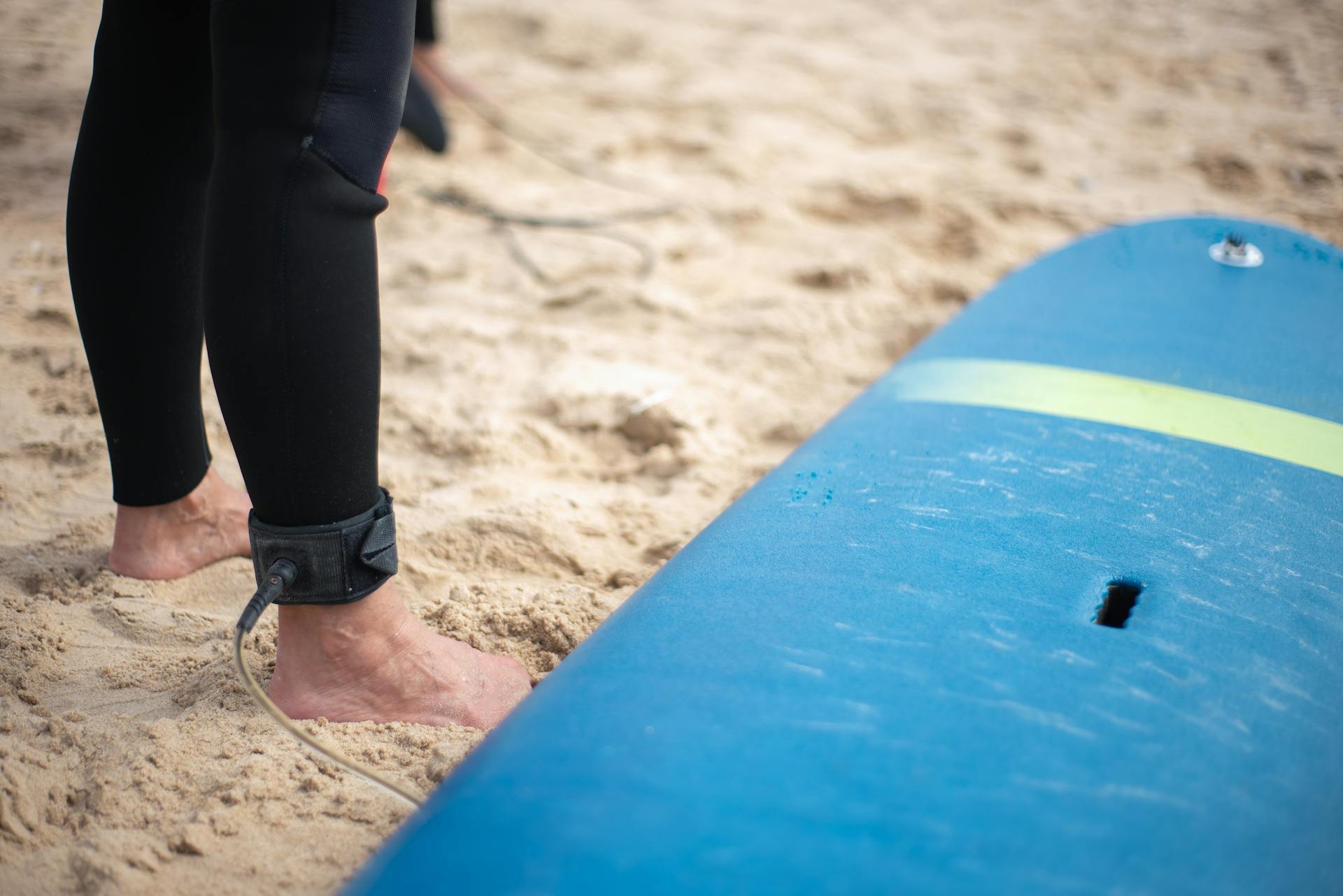 Surfer's feet and board ready on sandy Portugal beach. Perfect for summer vibes.
