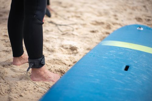 Free Surfer's feet and board ready on sandy Portugal beach. Perfect for summer vibes. Stock Photo