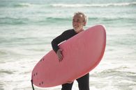 Man in Black Long Sleeve Shirt Holding Red Surfboard