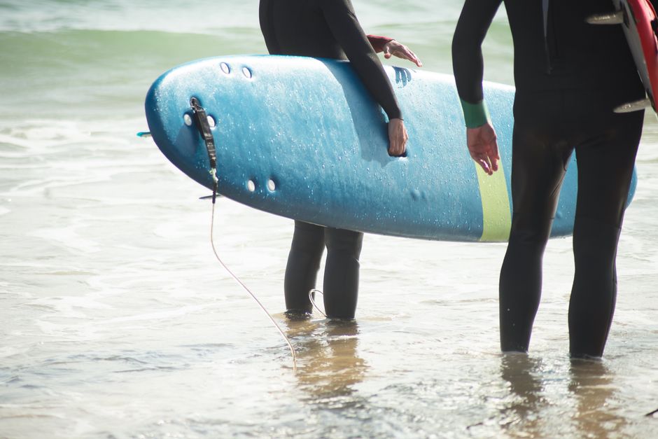 Surfers holding boards at a beach in Portugal, ready to catch the waves.