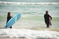 Man in Black Long Sleeve Shirt Holding Blue Surfboard on Beach