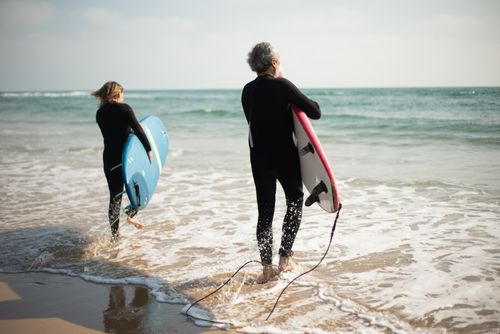 Free Adult surfers with surfboards head into the ocean on a sunny day in Portugal. Stock Photo