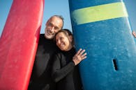 微笑的夫妇拿着冲浪板在一个阳光明媚的海滩，享受休闲时间.