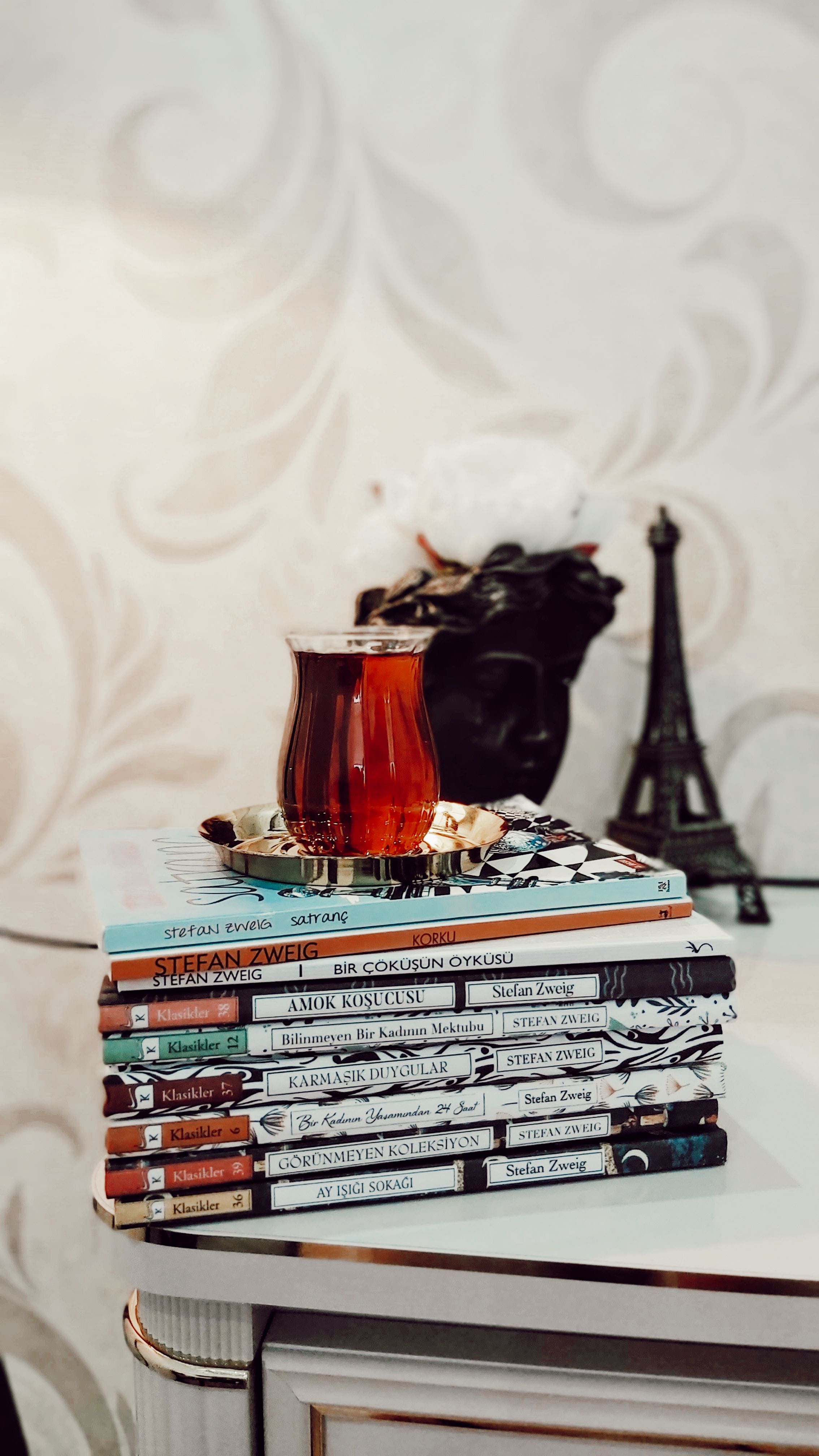 A stack of books with tea and decorative Eiffel Tower creating a cozy reading nook.