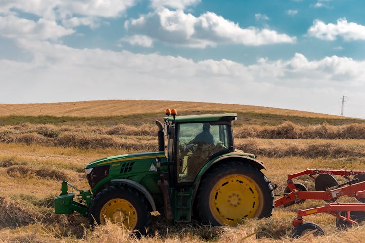 Green Tractor With Chisel Plow On Brown Hayfield