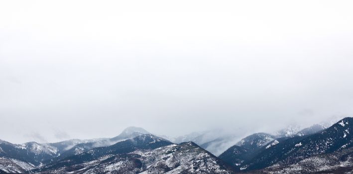 在阴云密布的天空下，白雪覆盖的山脉展现出壮丽景色，捕捉到了冬季的精髓