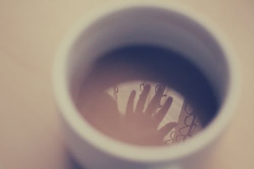 Silhouette of Hand in White Ceramic Cup