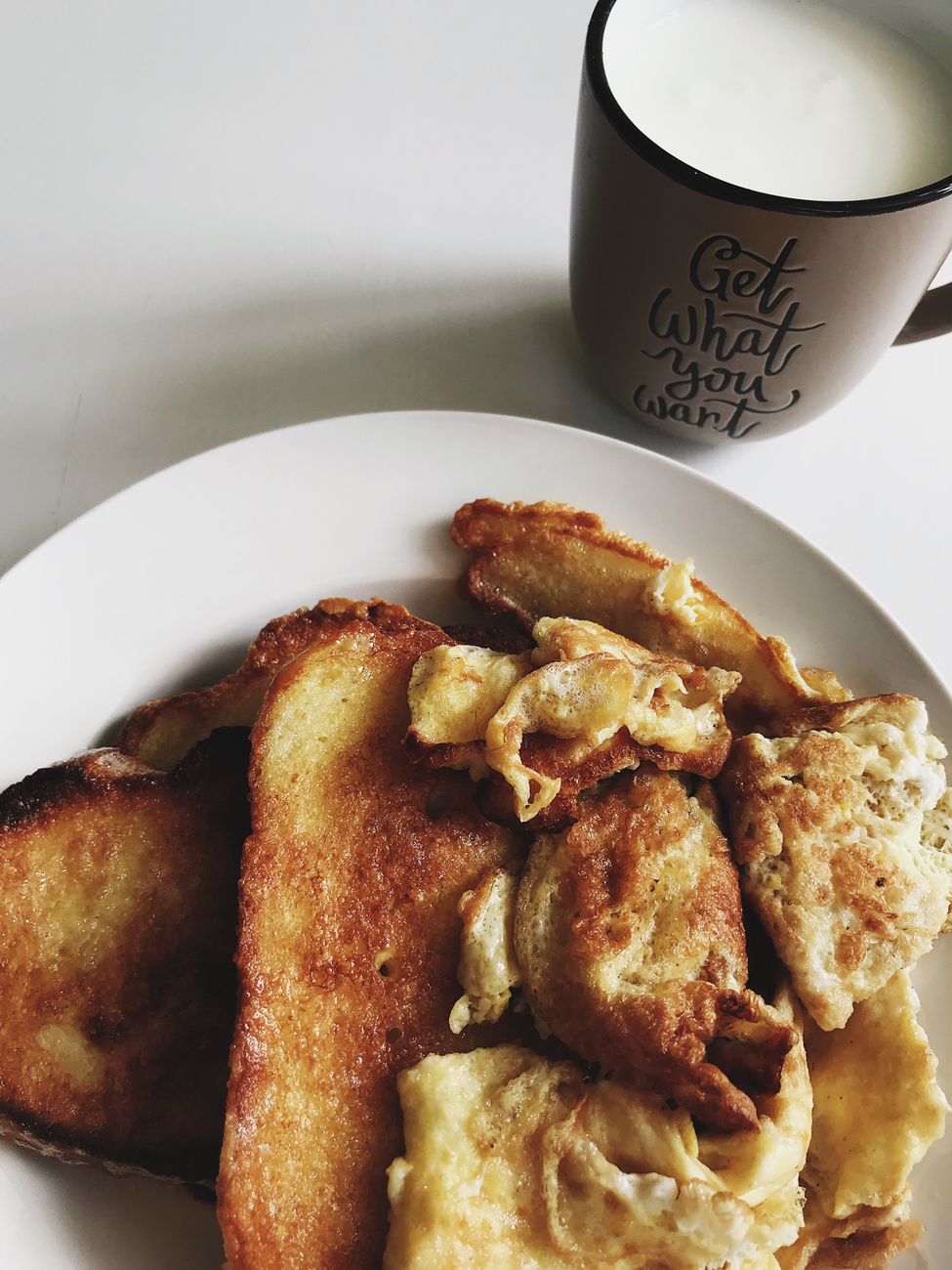 Delicious homemade French toast and eggs with a cup of milk for breakfast.