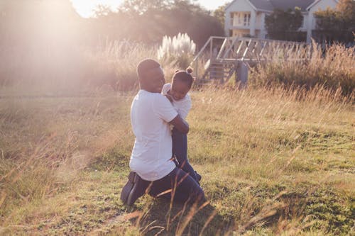 Father Hugging Daughter on Green Grass Field