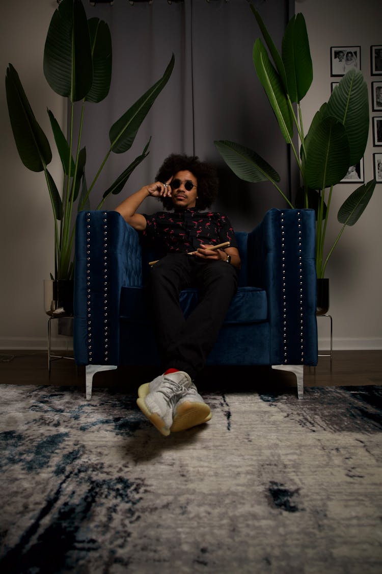 Man Sitting On Blue  Between Green Indoor Plants