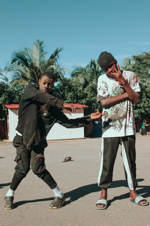 Free Two young men performing dance moves on a sunny street, expressing vibrant urban style. Stock Photo