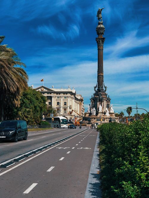 Free A stunning view of the Columbus Monument in Barcelona framed by a vivid blue sky and lively city street. Stock Photo