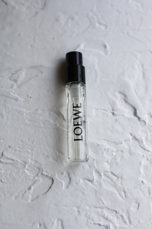 Clear Glass Spray Bottle with Perfume on White Surface