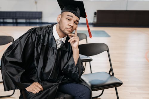 Free Photo of Man in Black Academic Dress Sitting on Chair Stock Photo