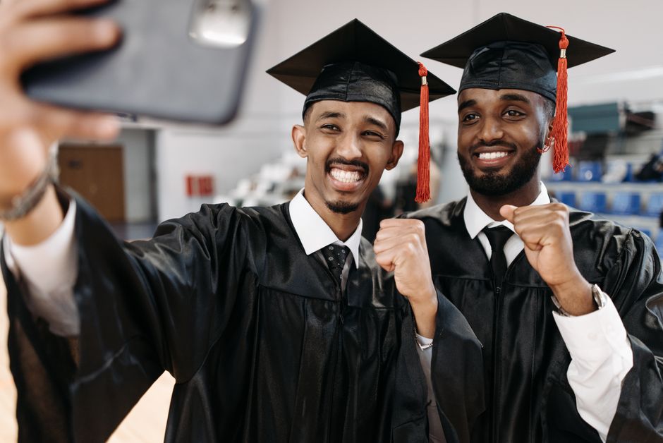 Two graduates take a celebratory selfie, showcasing happiness and achievement. Two graduates take a celebratory selfie, showcasing happiness and achievement.