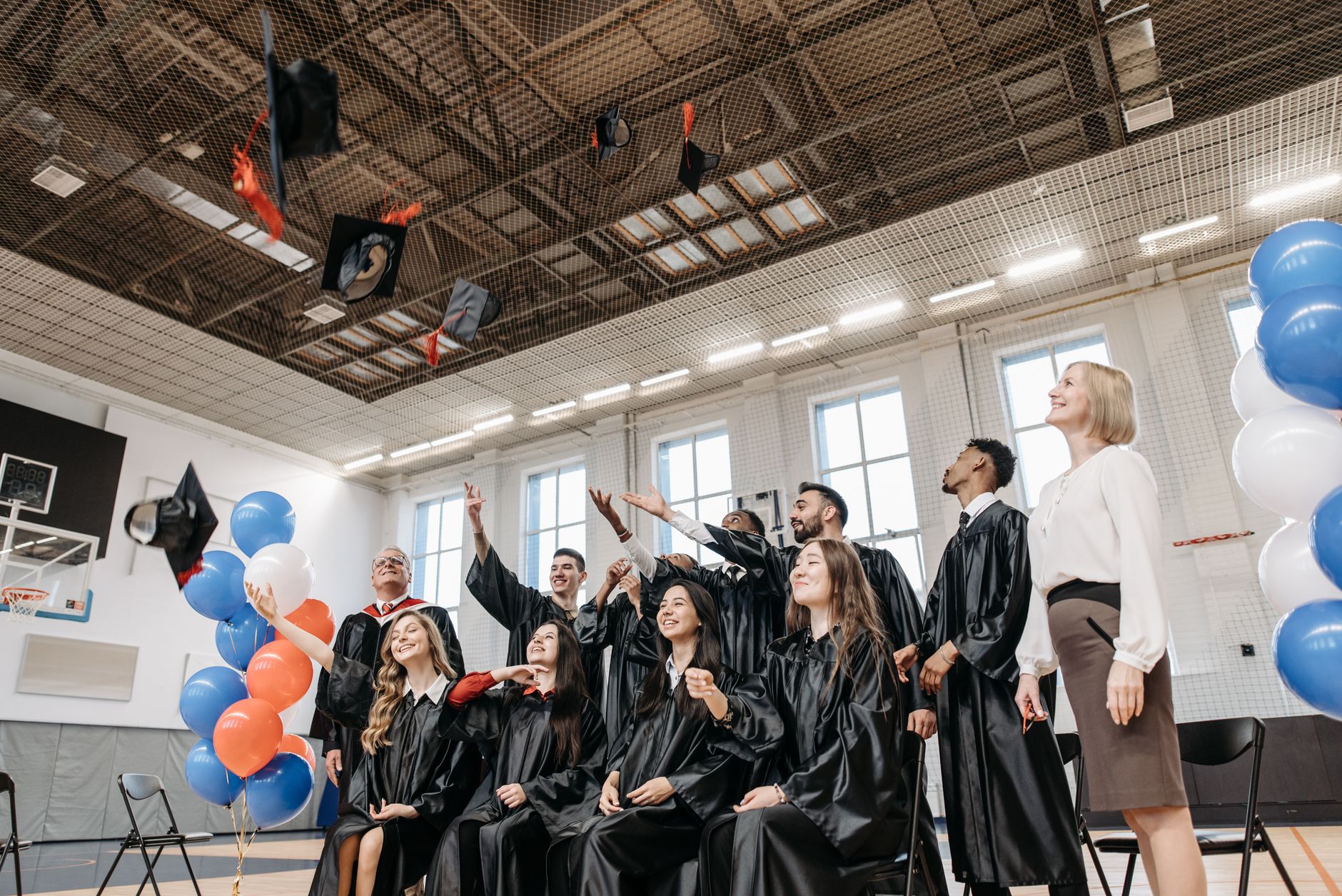 Graduates celebrating indoors with caps in the air, symbolizing achievement.