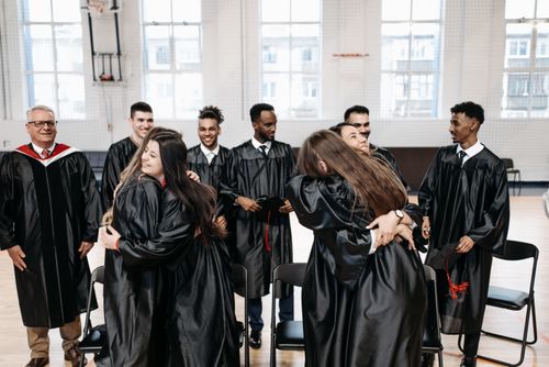 Free A joyful group of graduates hugging and celebrating their success in a gymnasium. Stock Photo