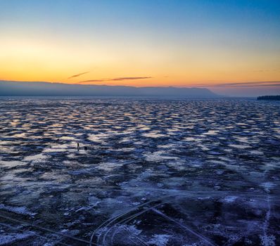 Stunning sunset over a frozen lake in Minnesota captured from above, showcasing vibrant winter colors.