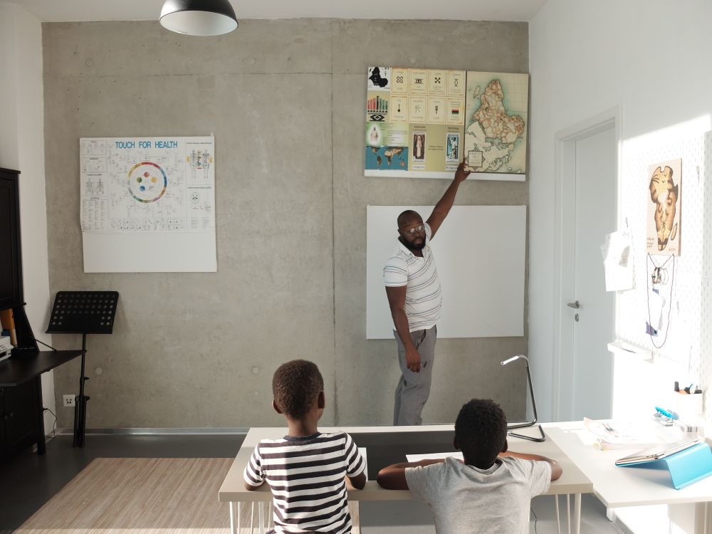 African male teacher guiding young primary school pupils in a bright classroom