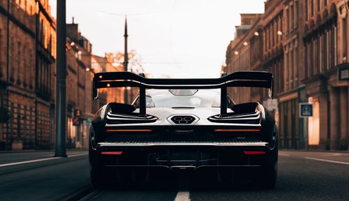 Free Captivating black sports car photographed from behind on a bustling city street, exuding speed and elegance. Stock Photo