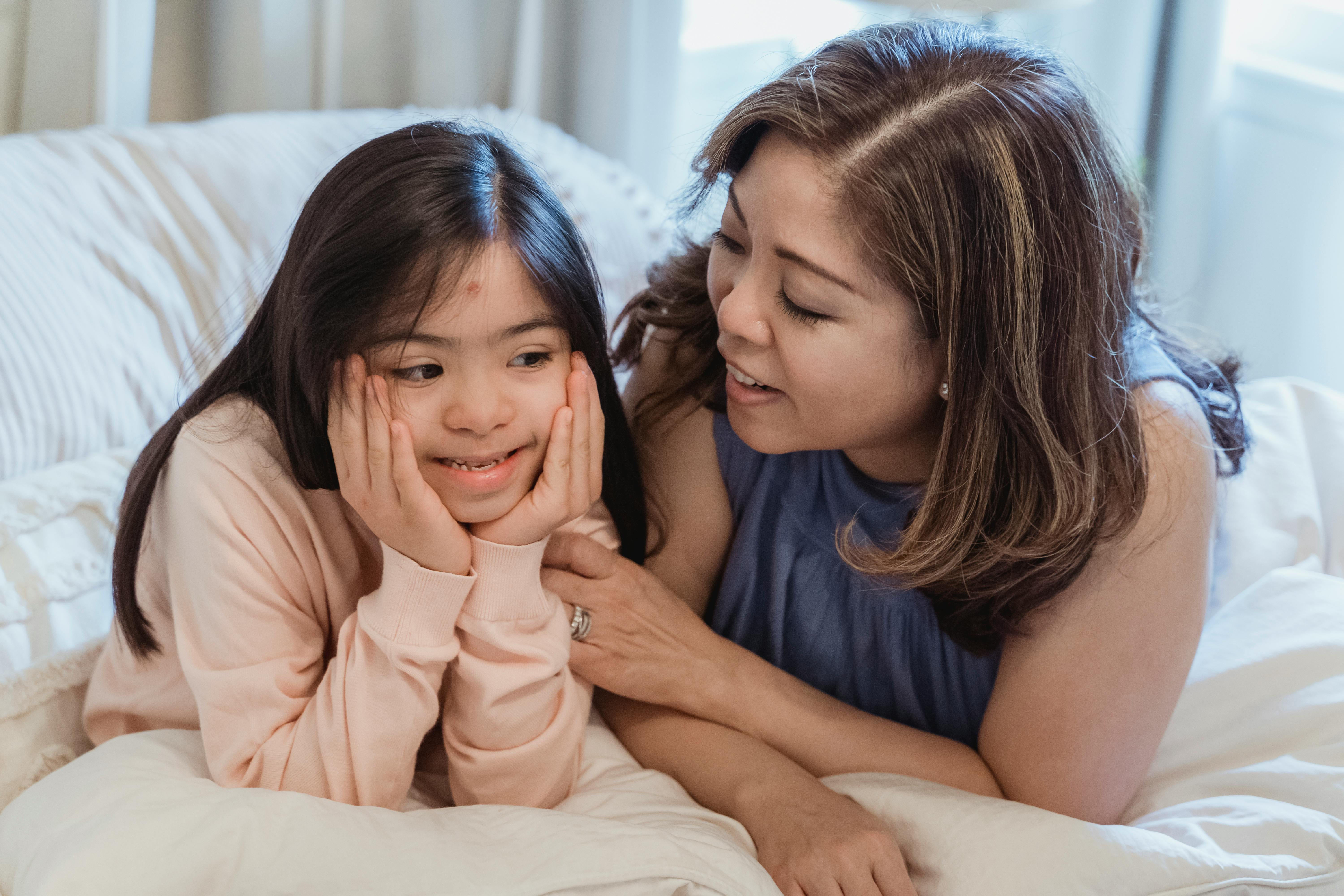 a woman and a young girl sitting on the bed