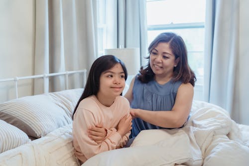 Free A Woman and a Young Girl Sitting on the Bed Stock Photo