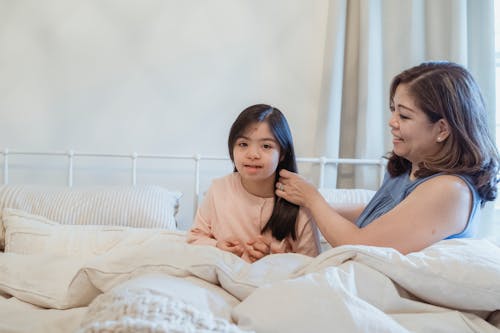 A Woman Fixing the Hair of a Young Girl