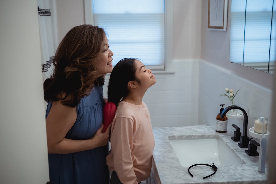 A mother and child standing in front of the bathroom mirror. 