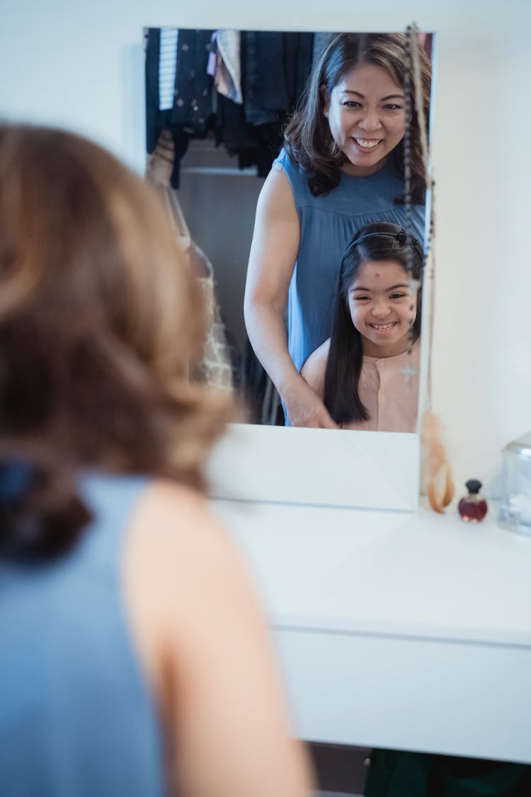 Mother And Daughter Looking At The Mirror