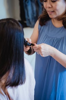 A mother braiding her daughter's hair in a cozy indoor environment, highlighting family bonding.