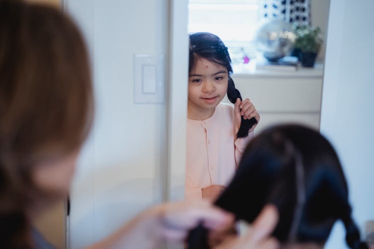 A Girl Looking The Mirror While Holding Her Hair