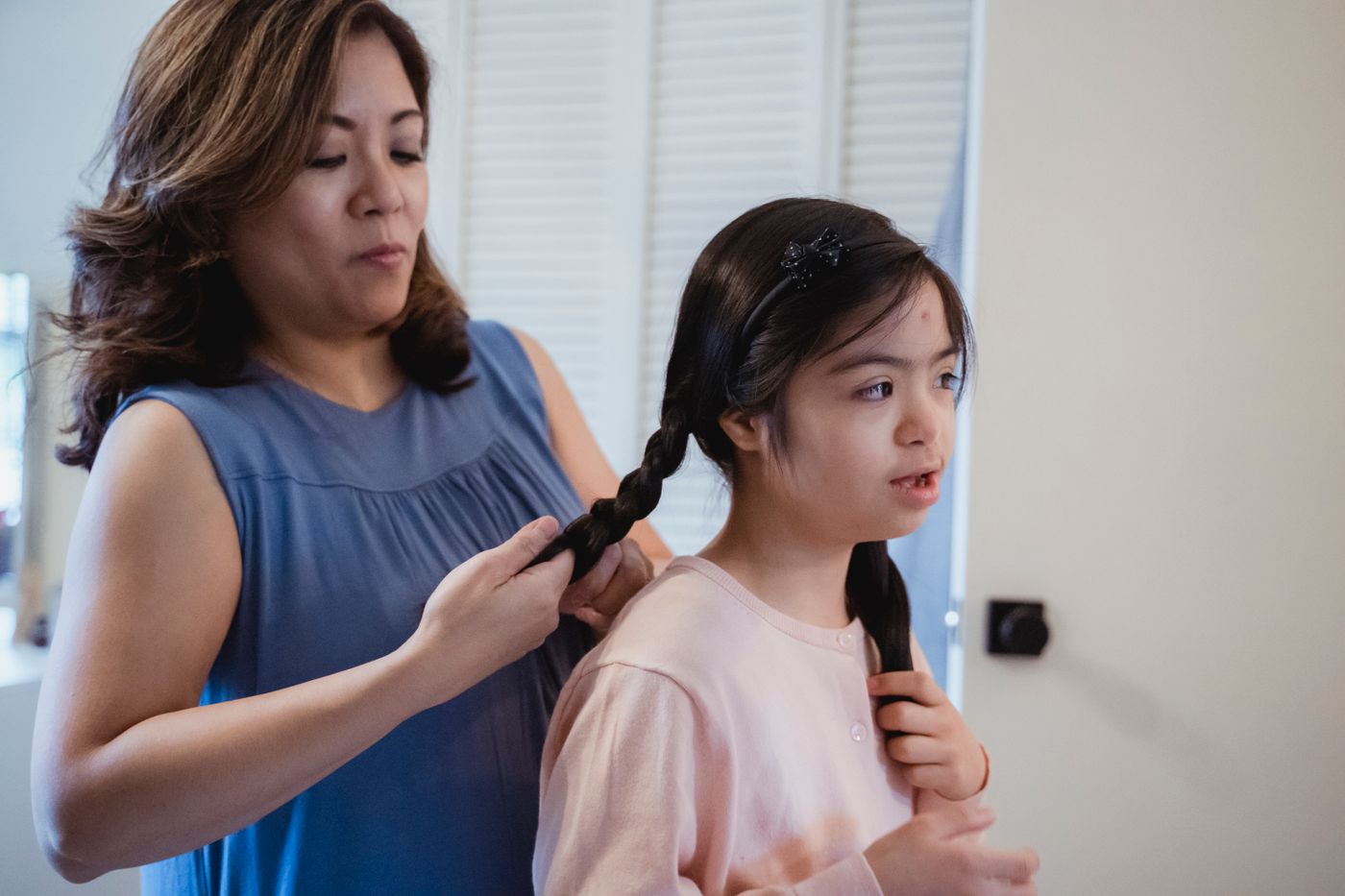 Mother carefully braiding her daughter's long hair during a relaxed family hair routine at home