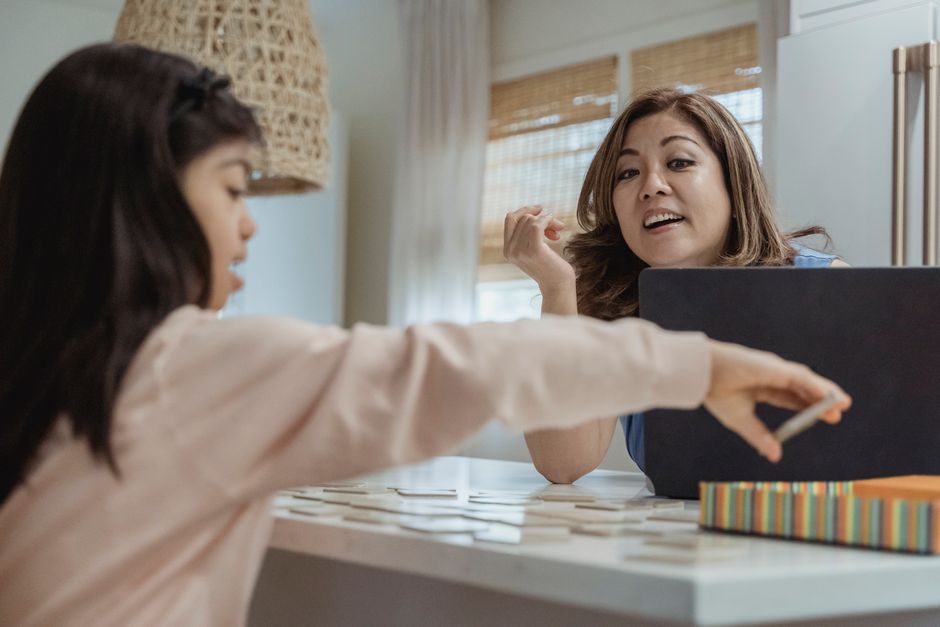 Mother and daughter enjoying a fun bonding moment playing a game at home. Candid and engaging.