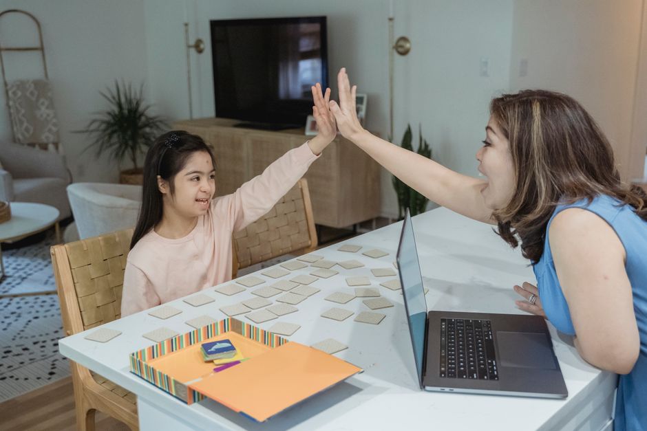 Happy mother and daughter high-fiving while playing a memory game at home.