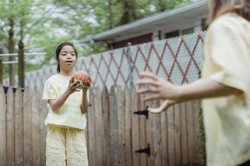 Free A young girl with Down syndrome playing outdoors with a basketball, enjoying a sunny day. Stock Photo