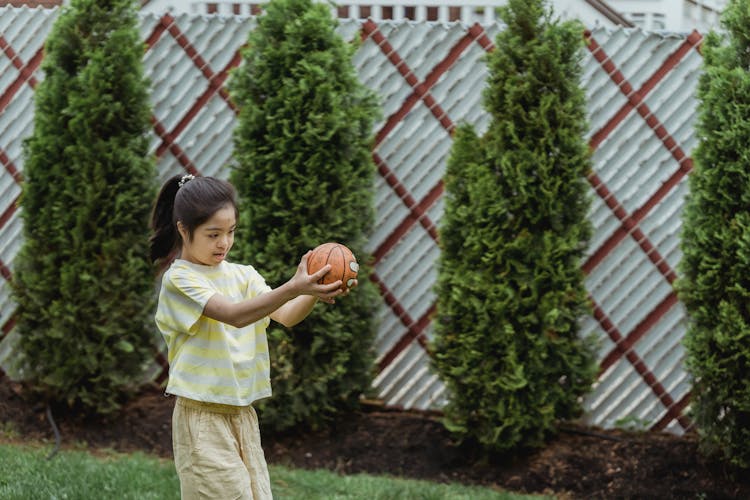 A Girl In A Striped Shirt Holding A Ball