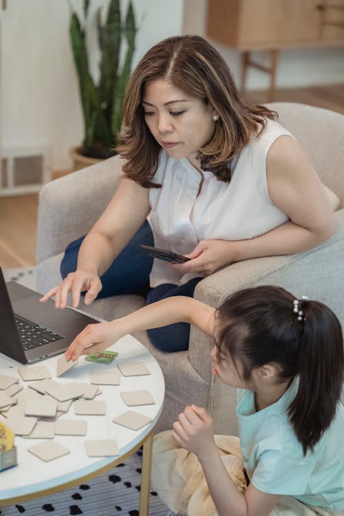 Free A Mother Working while Sitting Beside Her Daughter Stock Photo