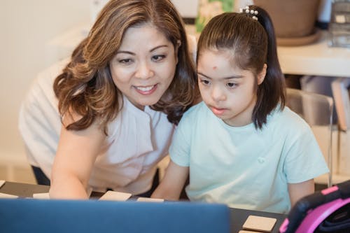 Free A woman and young girl using a computer together, showcasing family bonding and technology learning. Stock Photo