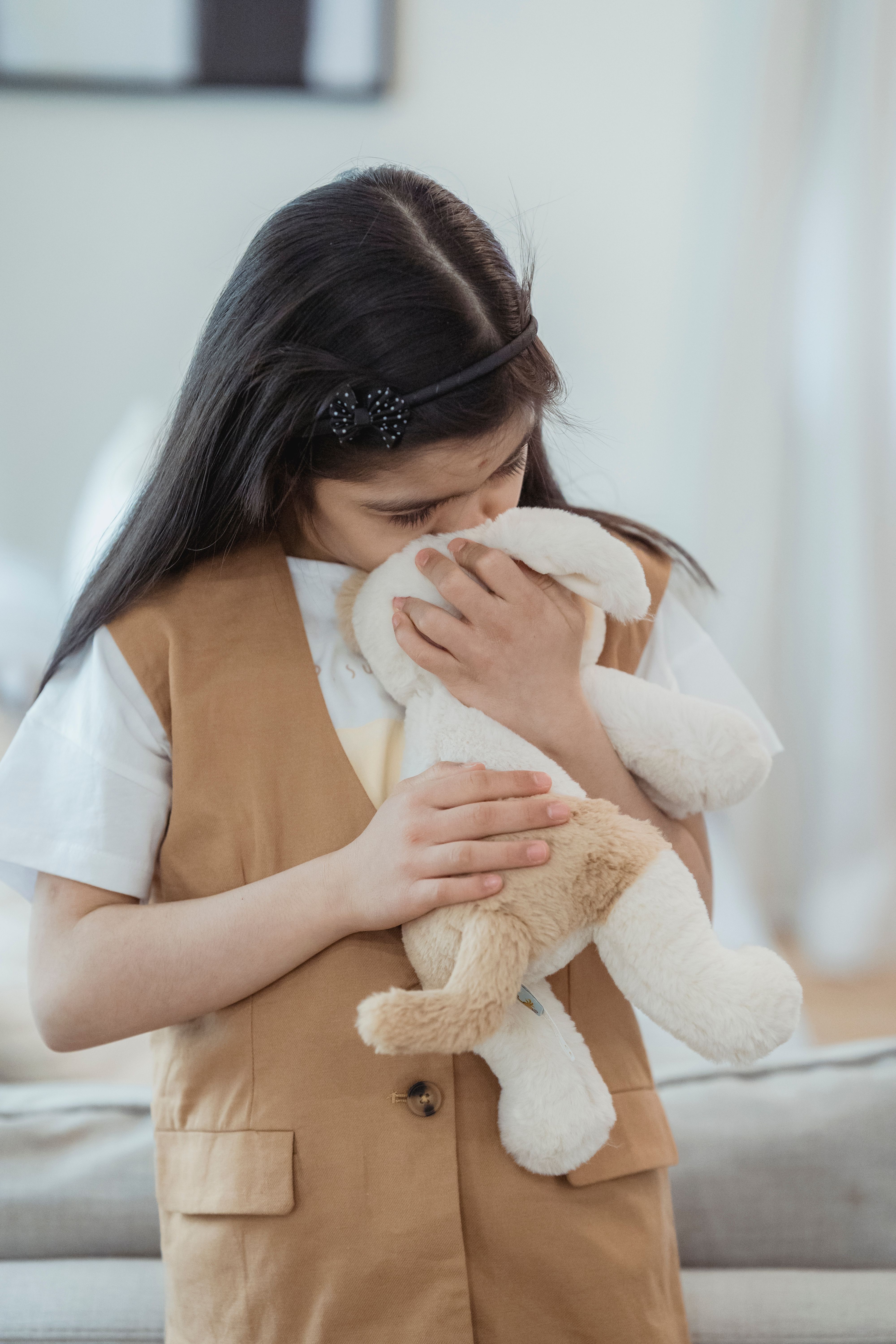 A young girl embraces a stuffed animal, showcasing love and tenderness indoors.