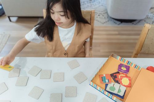 Free Young girl plays a memory card game indoors, focused and entertained. Stock Photo