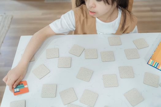 Young child playing a memory card game on a white table. High-angle view indoors.