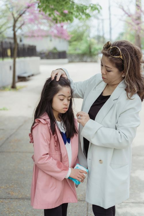 Free A caring mother wipes her daughter's face outdoors on a spring day, showcasing family love. Stock Photo