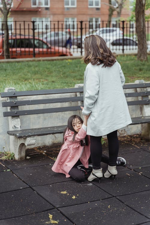 A Woman Holding a Young Girl while Sitting on the Ground