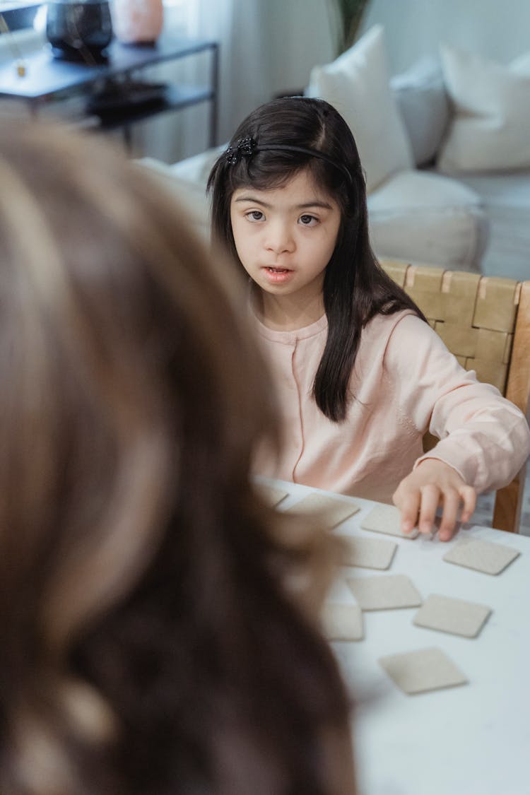 Girl Sitting By A Table Playing A Card Game