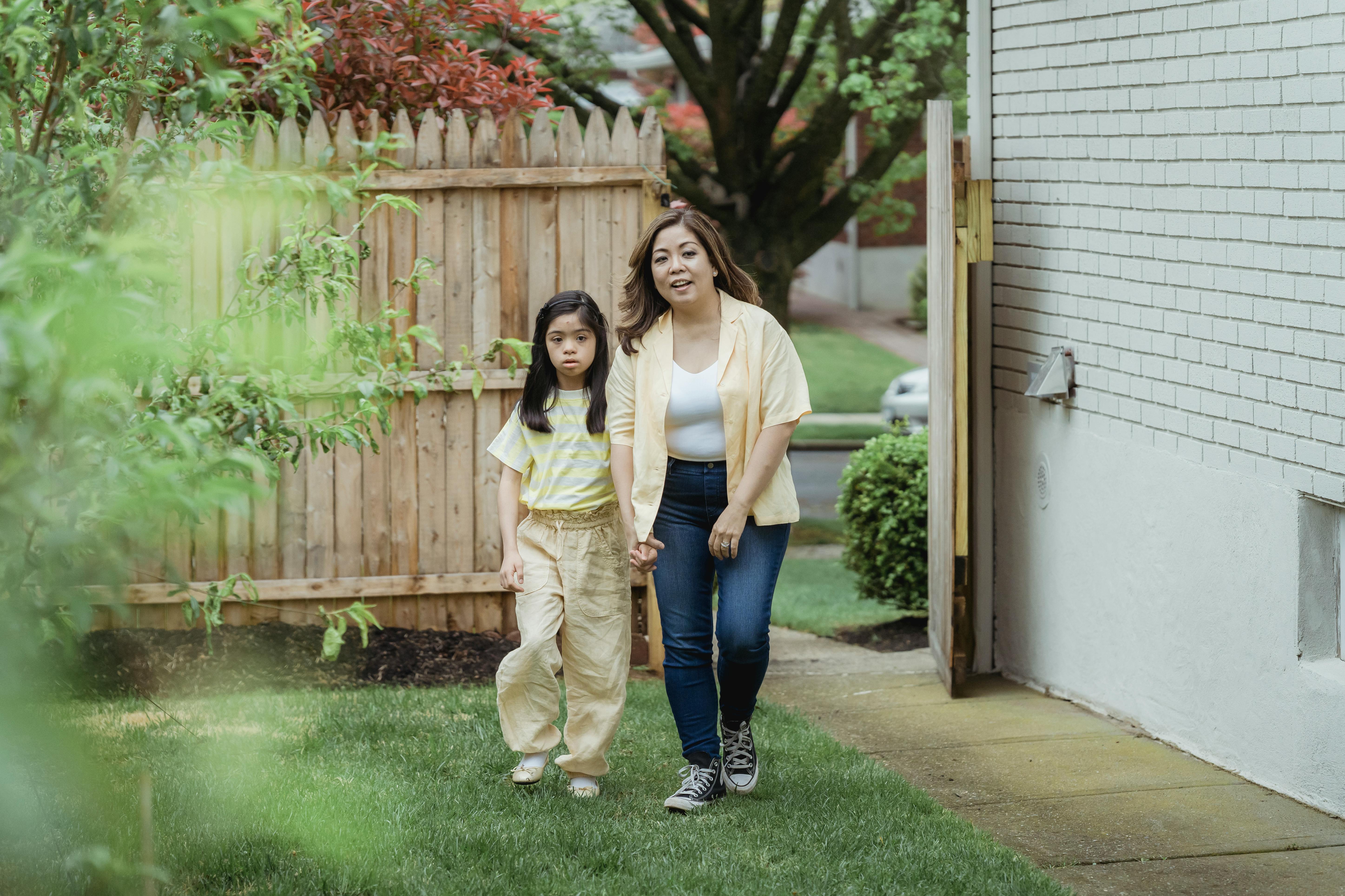 a woman holding a young girl while walking on the yard