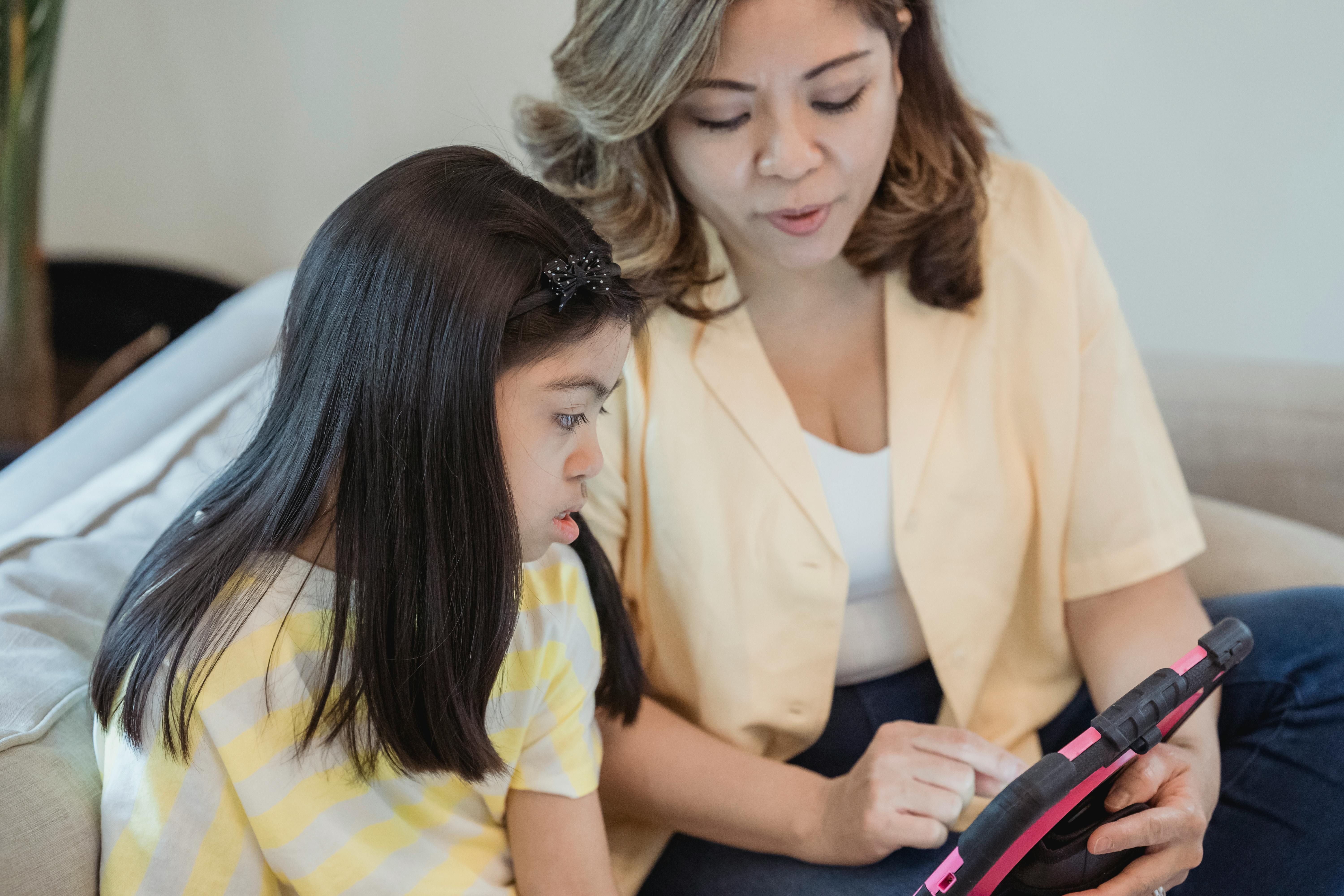 a woman and a young girl using a tablet