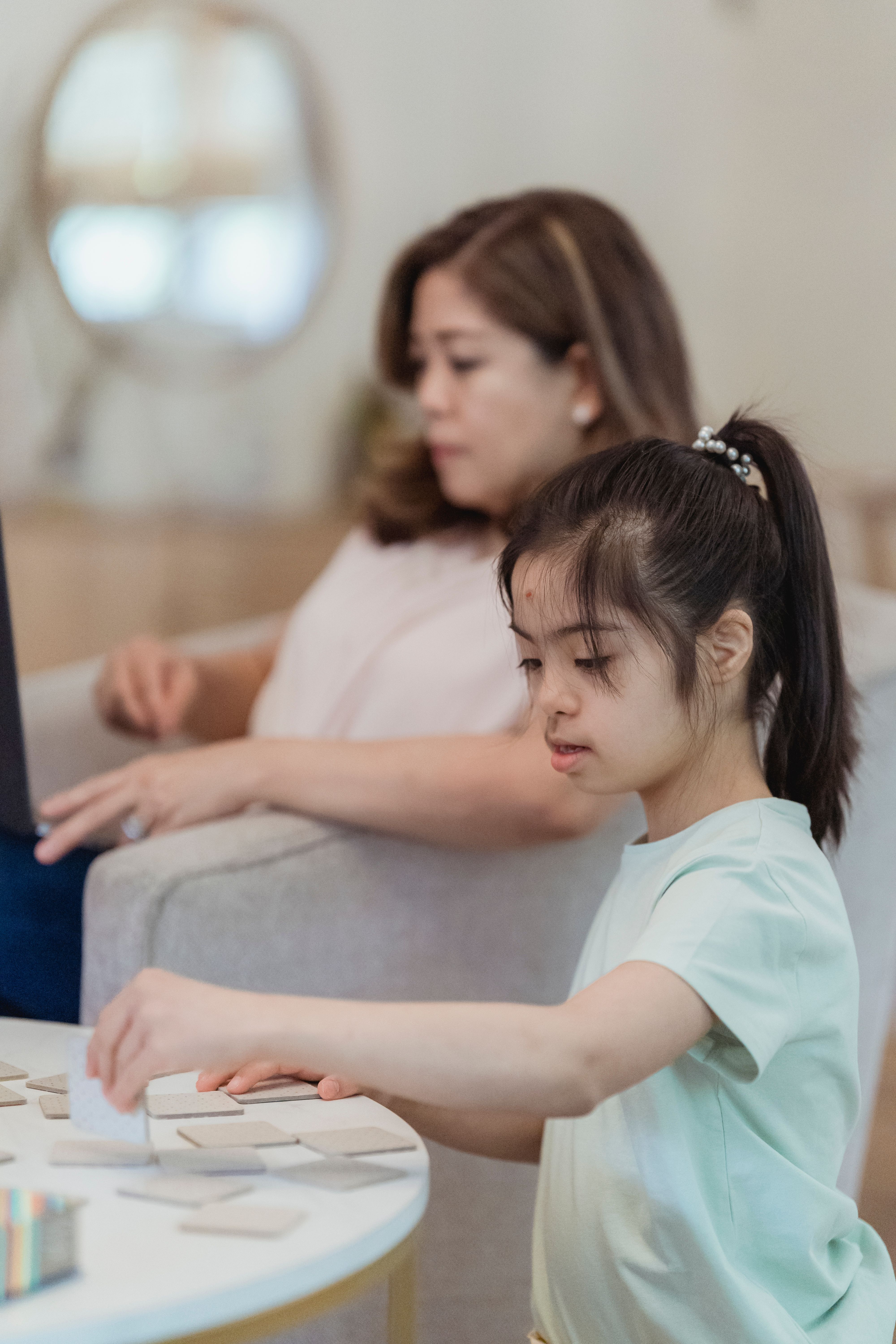 Young girl with Down syndrome playing a board game with her mother